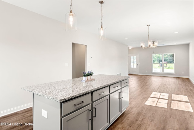 kitchen featuring gray cabinetry, wood finished floors, baseboards, a center island, and decorative light fixtures