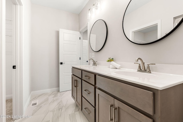 full bathroom with marble finish floor, double vanity, a sink, and baseboards