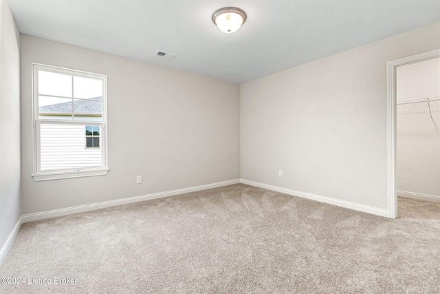 unfurnished bedroom featuring carpet, a closet, visible vents, a spacious closet, and baseboards