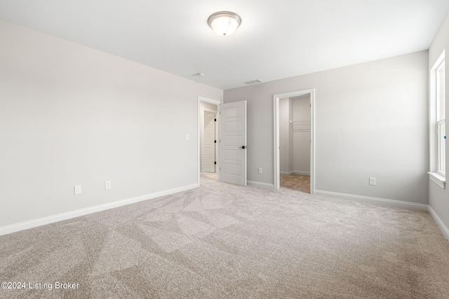 unfurnished bedroom with visible vents, baseboards, carpet, a walk in closet, and a closet