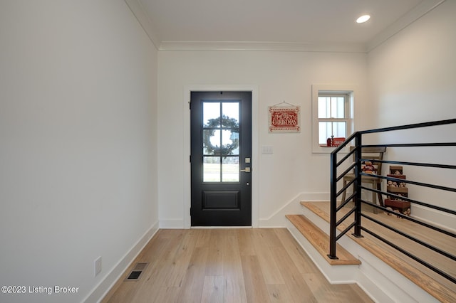 foyer entrance with crown molding and light hardwood / wood-style flooring