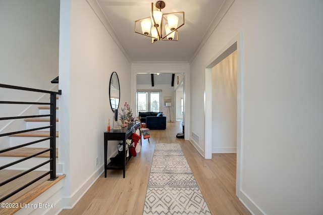 hall with ornamental molding, an inviting chandelier, and light wood-type flooring