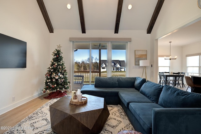 living room featuring a notable chandelier, lofted ceiling with beams, and light wood-type flooring