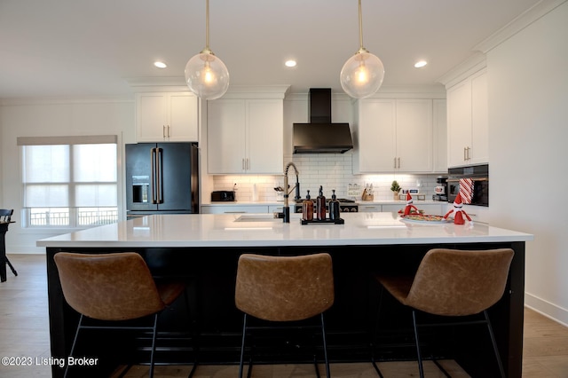 kitchen featuring white cabinetry, decorative light fixtures, black refrigerator with ice dispenser, and wall chimney range hood