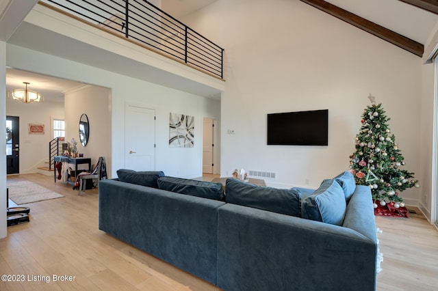 living room with high vaulted ceiling, an inviting chandelier, beam ceiling, and light hardwood / wood-style flooring