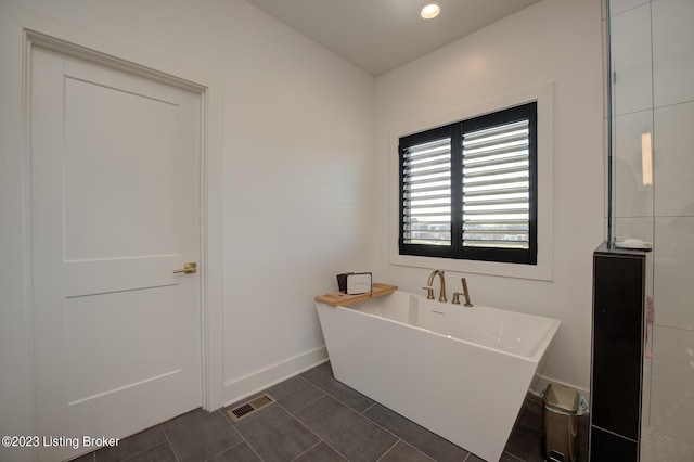 bathroom with tile patterned floors and a tub