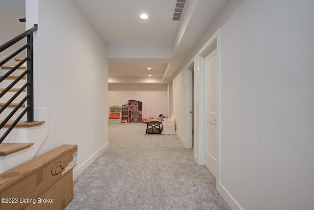 hall with light colored carpet and a tray ceiling