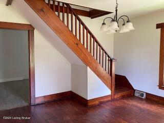 stairs featuring wood-type flooring and a chandelier