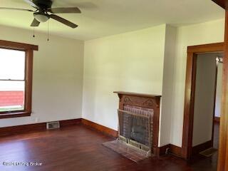 unfurnished living room with a fireplace, dark hardwood / wood-style floors, and ceiling fan