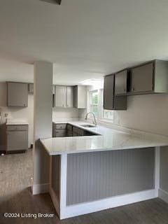 kitchen featuring kitchen peninsula, gray cabinets, dark wood-type flooring, and sink