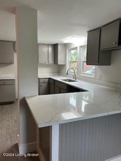 kitchen with gray cabinets, sink, and kitchen peninsula