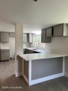 kitchen with kitchen peninsula, sink, dark hardwood / wood-style floors, and gray cabinetry