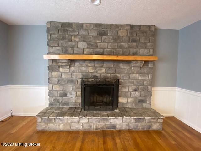 room details with hardwood / wood-style flooring, a textured ceiling, and a brick fireplace