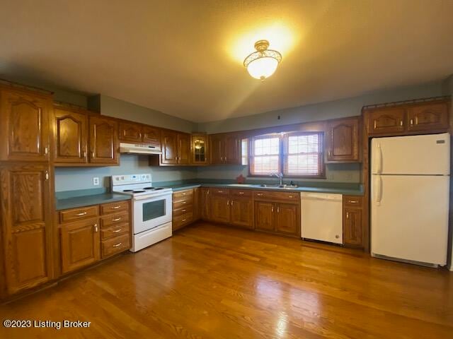 kitchen featuring white appliances, hardwood / wood-style flooring, sink, and lofted ceiling