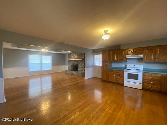 kitchen with wood-type flooring, a large fireplace, and white electric stove