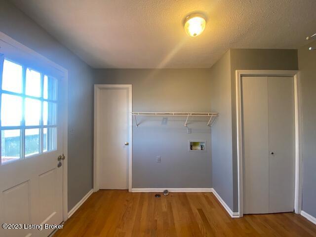 clothes washing area featuring hookup for a washing machine, wood-type flooring, and a textured ceiling