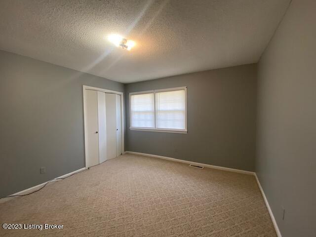 unfurnished bedroom featuring light carpet and a textured ceiling