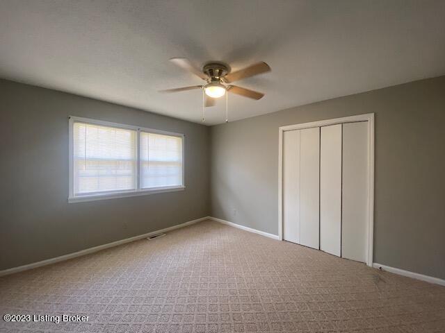 unfurnished bedroom with a closet, ceiling fan, and carpet floors