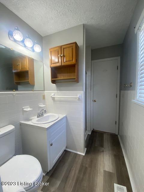 bathroom with vanity, hardwood / wood-style floors, tile walls, toilet, and decorative backsplash