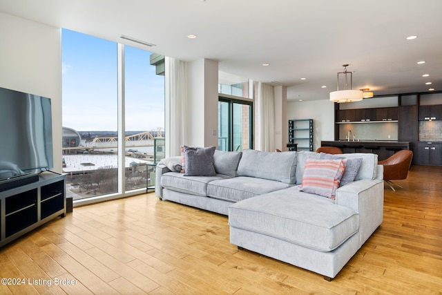 living room with floor to ceiling windows, light hardwood / wood-style flooring, and sink