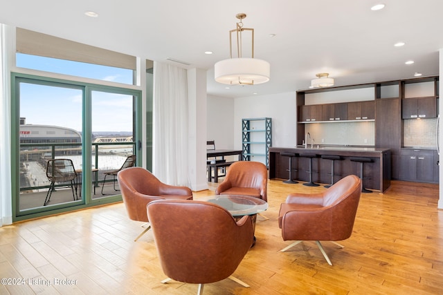 living room with floor to ceiling windows, sink, and light wood-type flooring