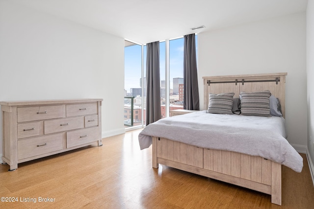 bedroom with expansive windows, access to exterior, and light wood-type flooring