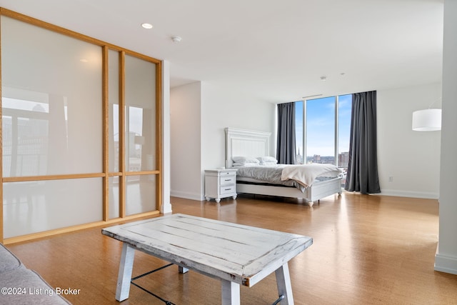 bedroom with floor to ceiling windows and light hardwood / wood-style flooring