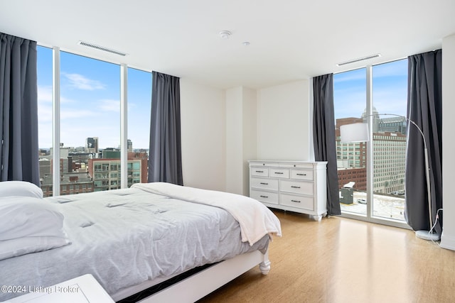 bedroom with floor to ceiling windows, light hardwood / wood-style flooring, and access to outside