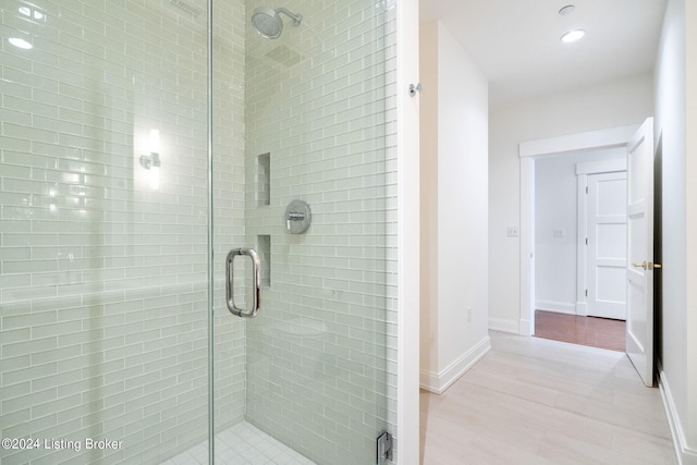 bathroom with a shower with shower door and wood-type flooring