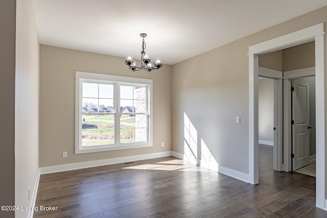 unfurnished room with dark hardwood / wood-style flooring and an inviting chandelier