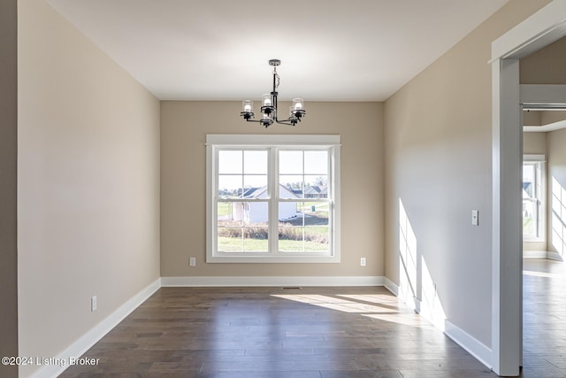 unfurnished dining area featuring dark hardwood / wood-style floors and a chandelier