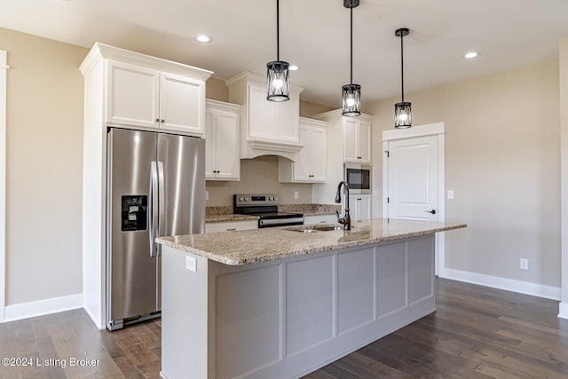 kitchen with stainless steel appliances, a kitchen island with sink, sink, white cabinets, and hanging light fixtures