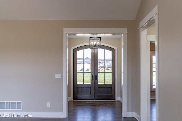 entrance foyer with a chandelier, vaulted ceiling, dark wood-type flooring, and french doors