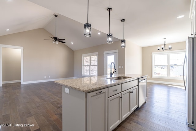 kitchen with light stone counters, stainless steel appliances, sink, lofted ceiling, and an island with sink