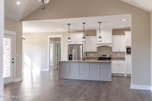 kitchen featuring a center island with sink, decorative light fixtures, stainless steel appliances, and vaulted ceiling