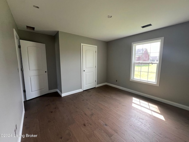 unfurnished bedroom featuring dark hardwood / wood-style flooring and a closet