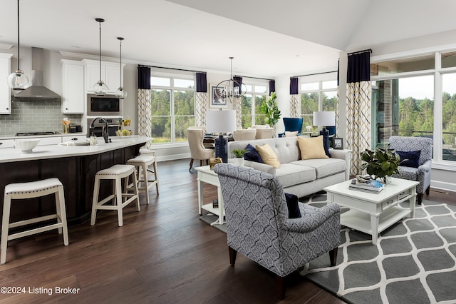 living room with dark hardwood / wood-style flooring, a notable chandelier, sink, and a wealth of natural light