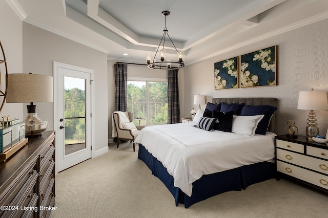 carpeted bedroom featuring access to exterior, ornamental molding, a chandelier, and a tray ceiling