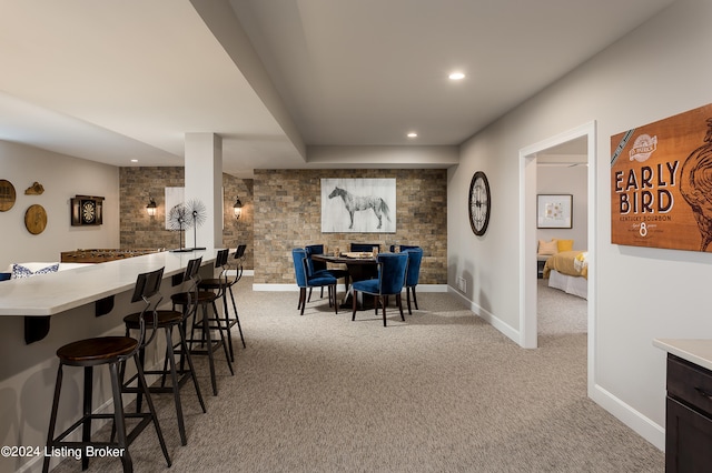 carpeted dining space with bar area and brick wall