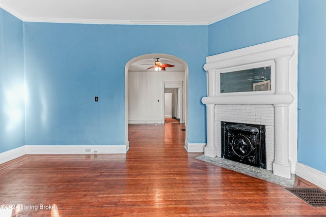 unfurnished living room featuring ornamental molding, ceiling fan, a brick fireplace, and dark wood-type flooring