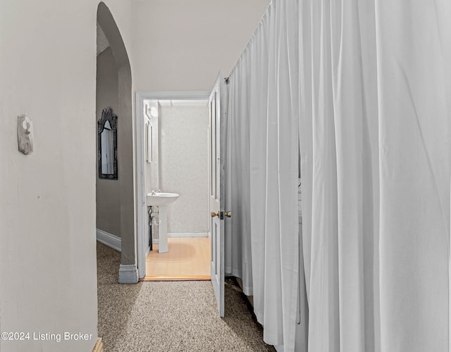 hallway with light carpet and sink