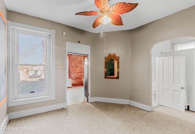 spare room featuring light colored carpet, ceiling fan, and a wealth of natural light