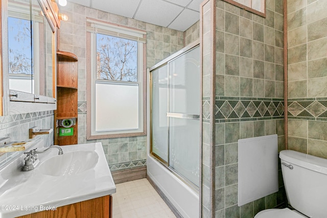 full bathroom featuring tile flooring, toilet, enclosed tub / shower combo, vanity, and tile walls