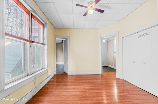 spare room featuring a drop ceiling, ceiling fan, and light wood-type flooring