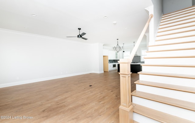 interior space with light hardwood / wood-style floors, ceiling fan with notable chandelier, and crown molding