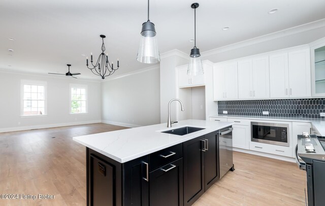 kitchen featuring light hardwood / wood-style flooring, a kitchen island with sink, black microwave, decorative backsplash, and sink