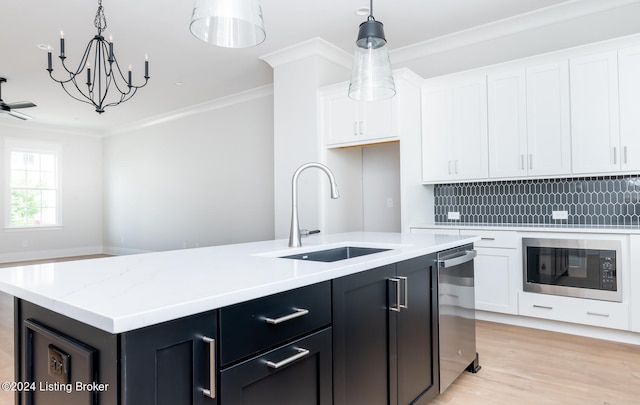 kitchen with black microwave, ornamental molding, light hardwood / wood-style floors, backsplash, and a kitchen island with sink