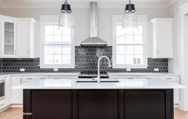 kitchen with wall chimney range hood, decorative backsplash, light hardwood / wood-style flooring, and a wealth of natural light