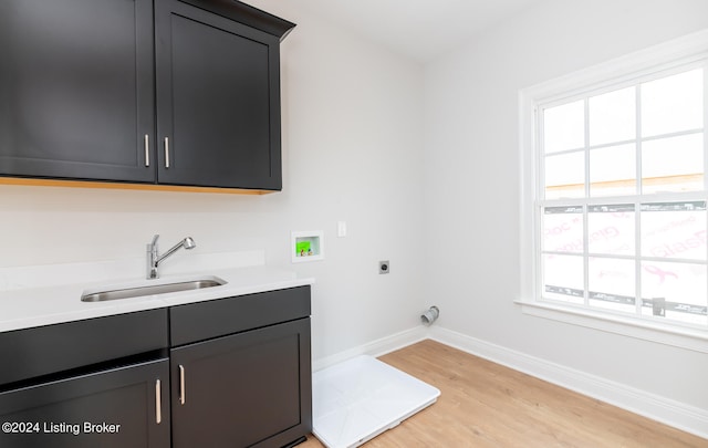 clothes washing area featuring light wood-type flooring, a wealth of natural light, washer hookup, electric dryer hookup, and sink