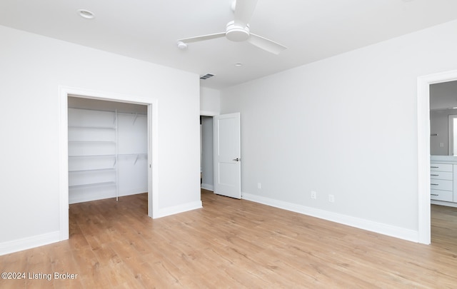 unfurnished bedroom with a spacious closet, ceiling fan, light hardwood / wood-style floors, and a closet